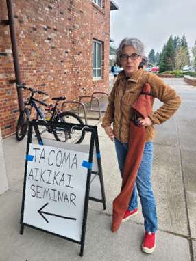 Dr. Sperlich standing in front of a sign that says "Tacoma Aikikai Seminar"